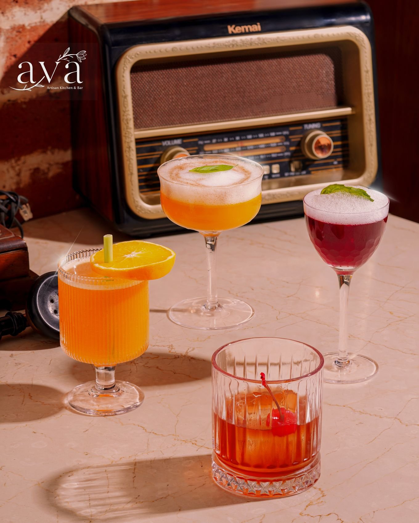 Orange highball and a cherry old fashioned on a marble bar