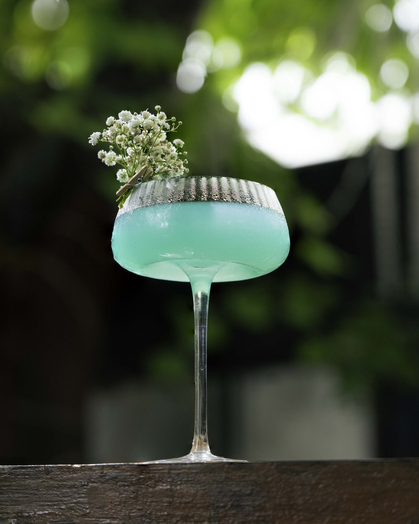 Blue cocktail with flowers in a coupe glass