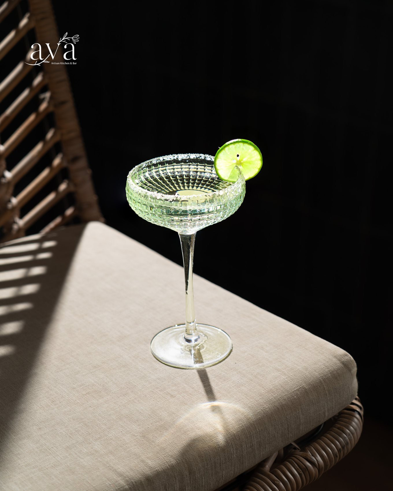 Cocktail with a lime wheel in a ribbed coupe glass